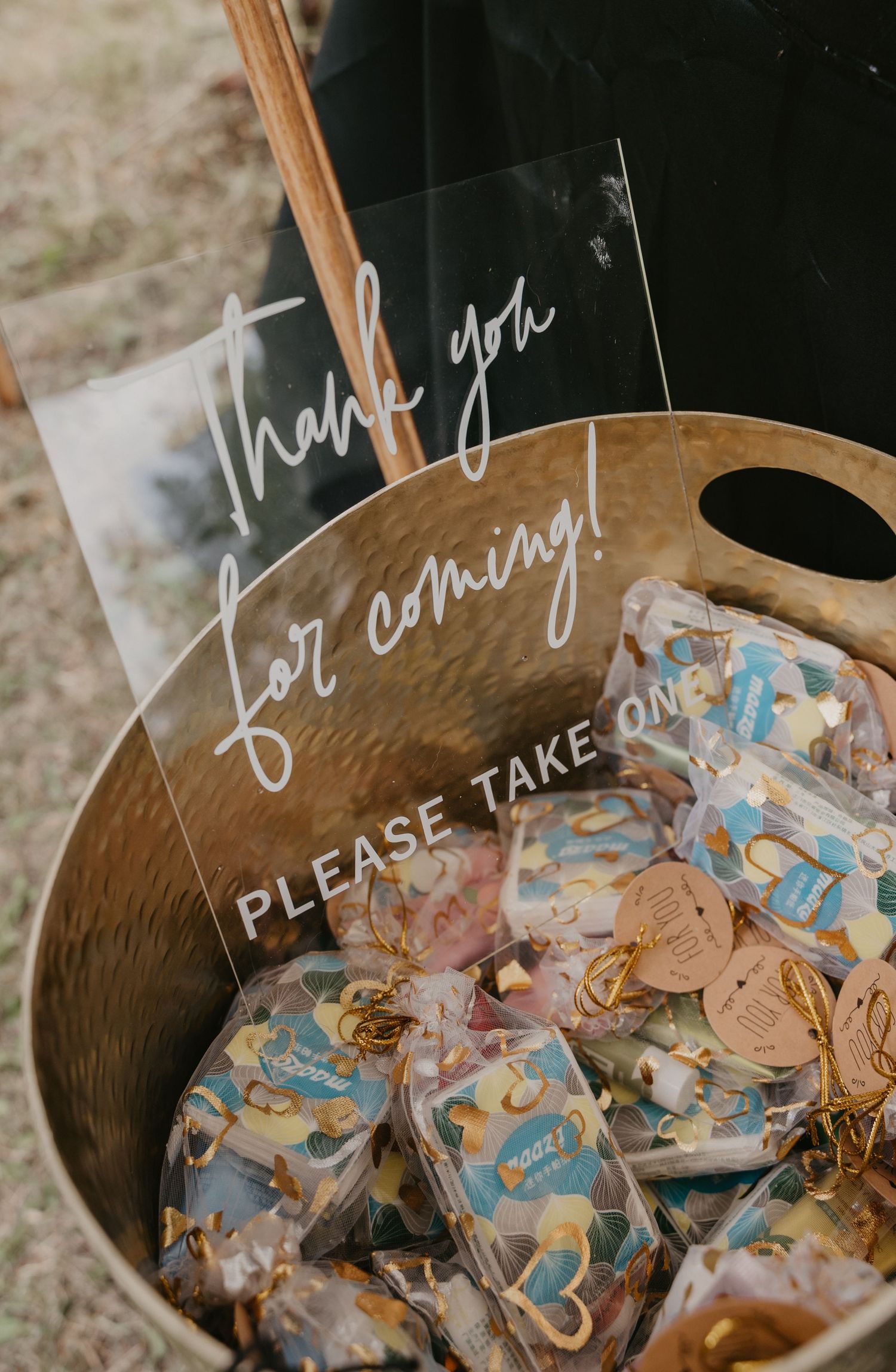 Wooden basket filled with individually wrapped wedding favor cookies and a handwritten sign.
