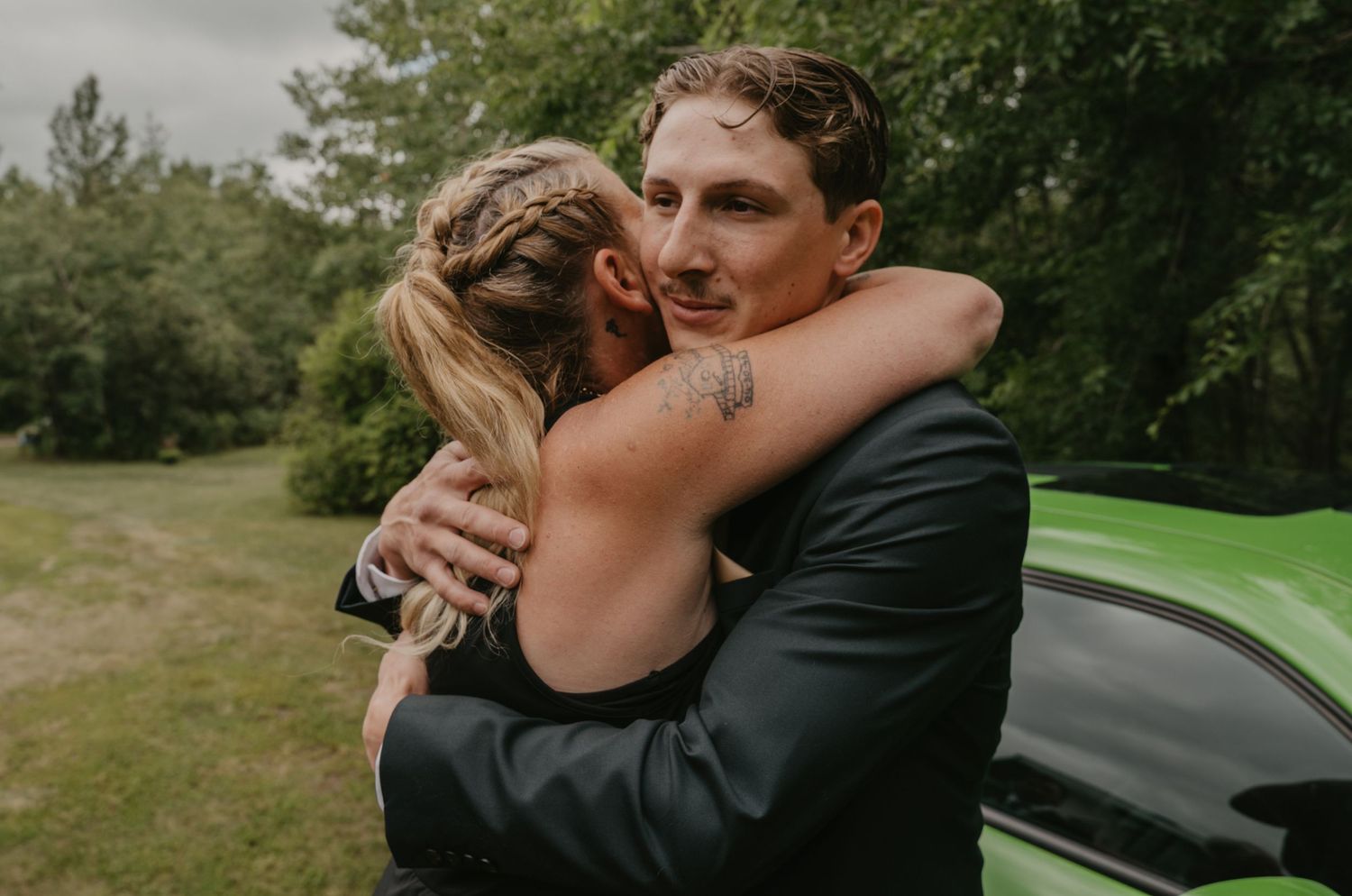Emotional embrace captured during an outdoor wedding ceremony with natural greenery in background.