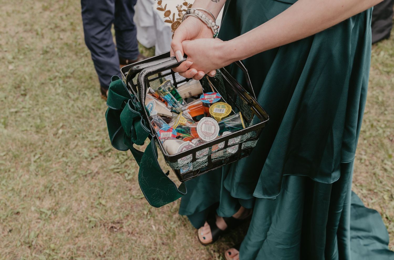 Wedding party members in emerald green dresses holding makeup bags during pre-ceremony preparations.
