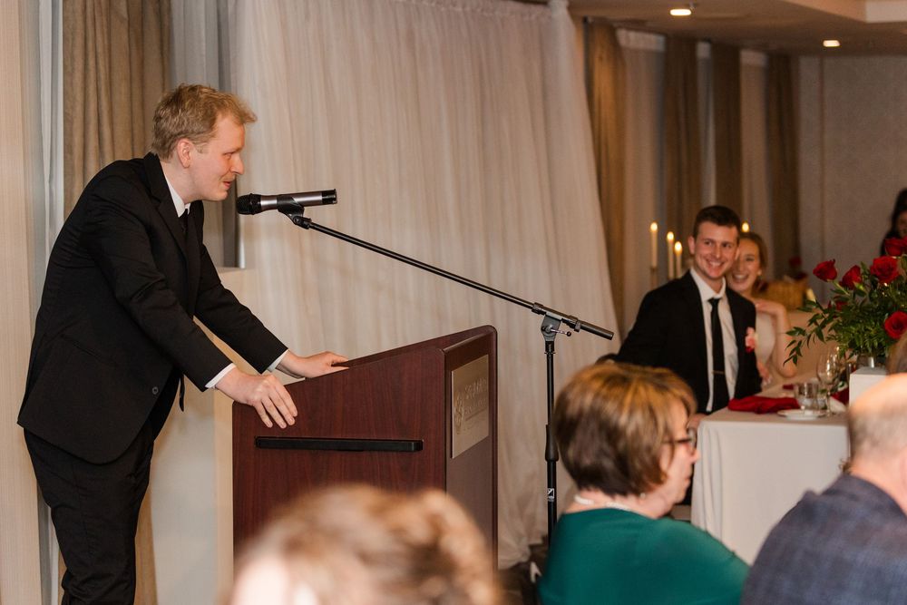 Audience members listening attentively during formal presentation at hotel venue.