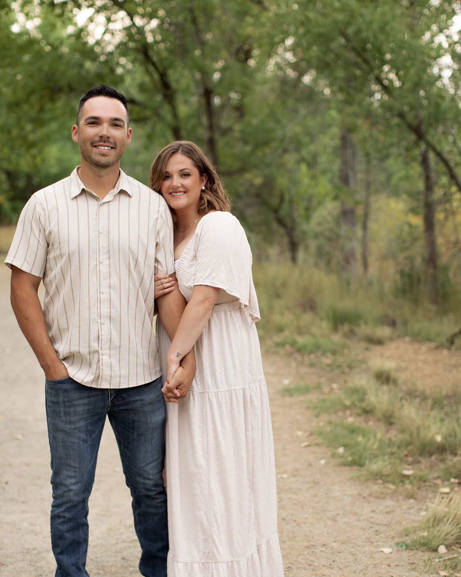 A couple in casual attire shares tender moments together while walking through a peaceful autumn forest.