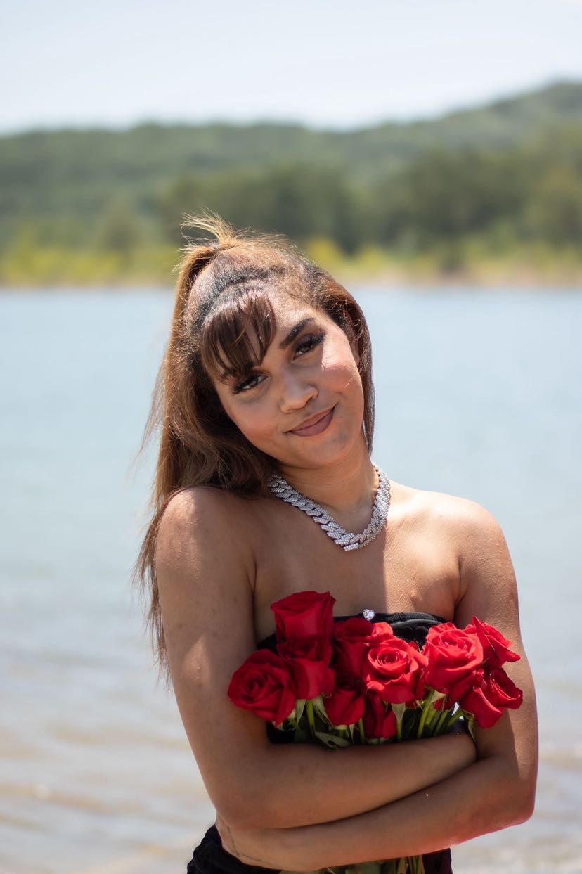 Woman standing by the lake with roses smiling.