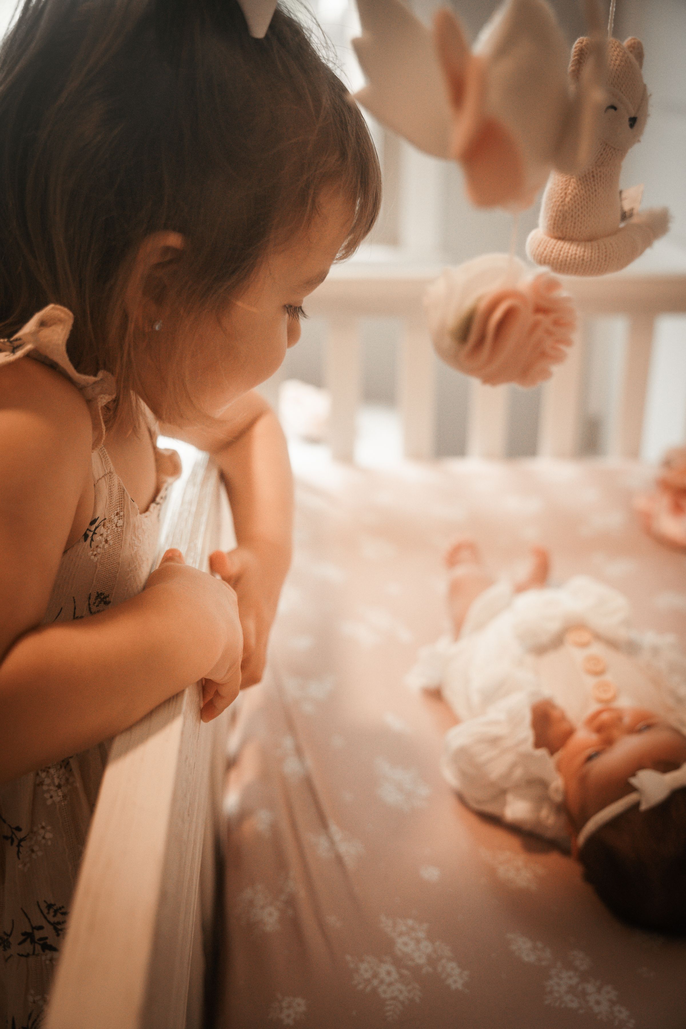 A sequence of intimate moments shows a newborn baby being tenderly cared for in a soft, warm-toned setting at newborn lifestyle session