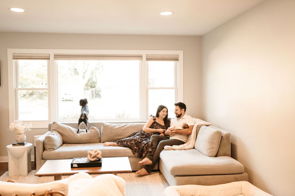 Cozy living room scene with family relaxing and cuddling their newborn baby during in home photo session