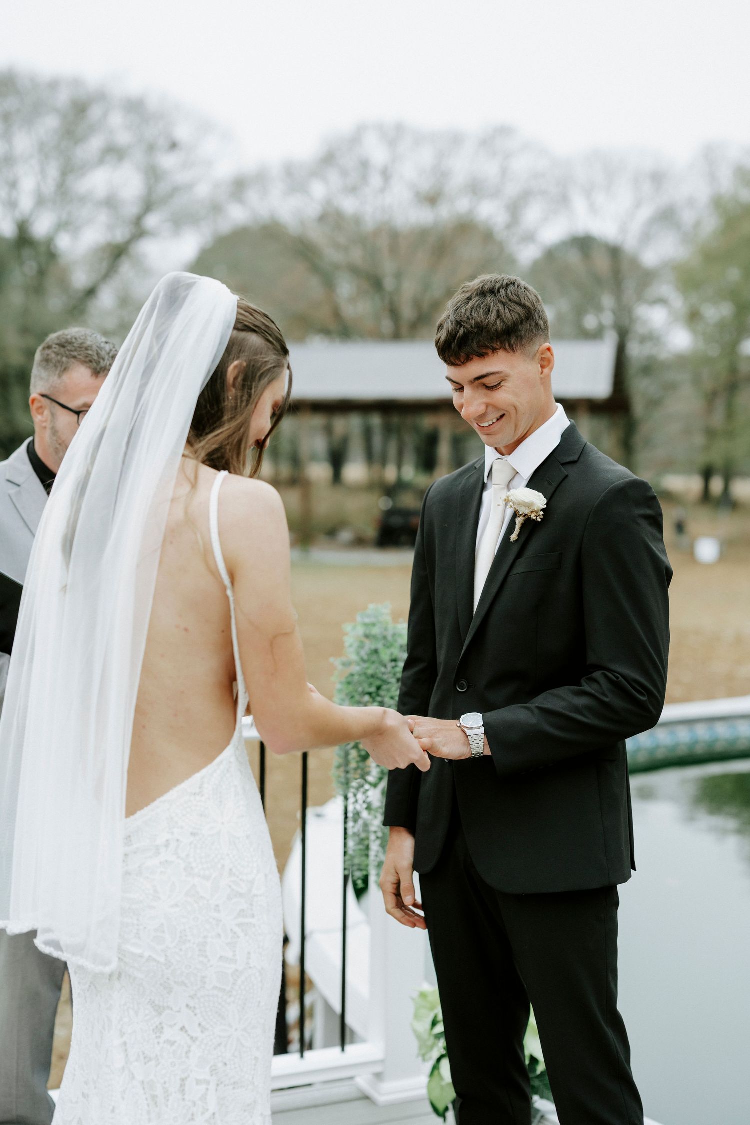 Bride and groom share a tender first look moment by a lake during their outdoor wedding ceremony.