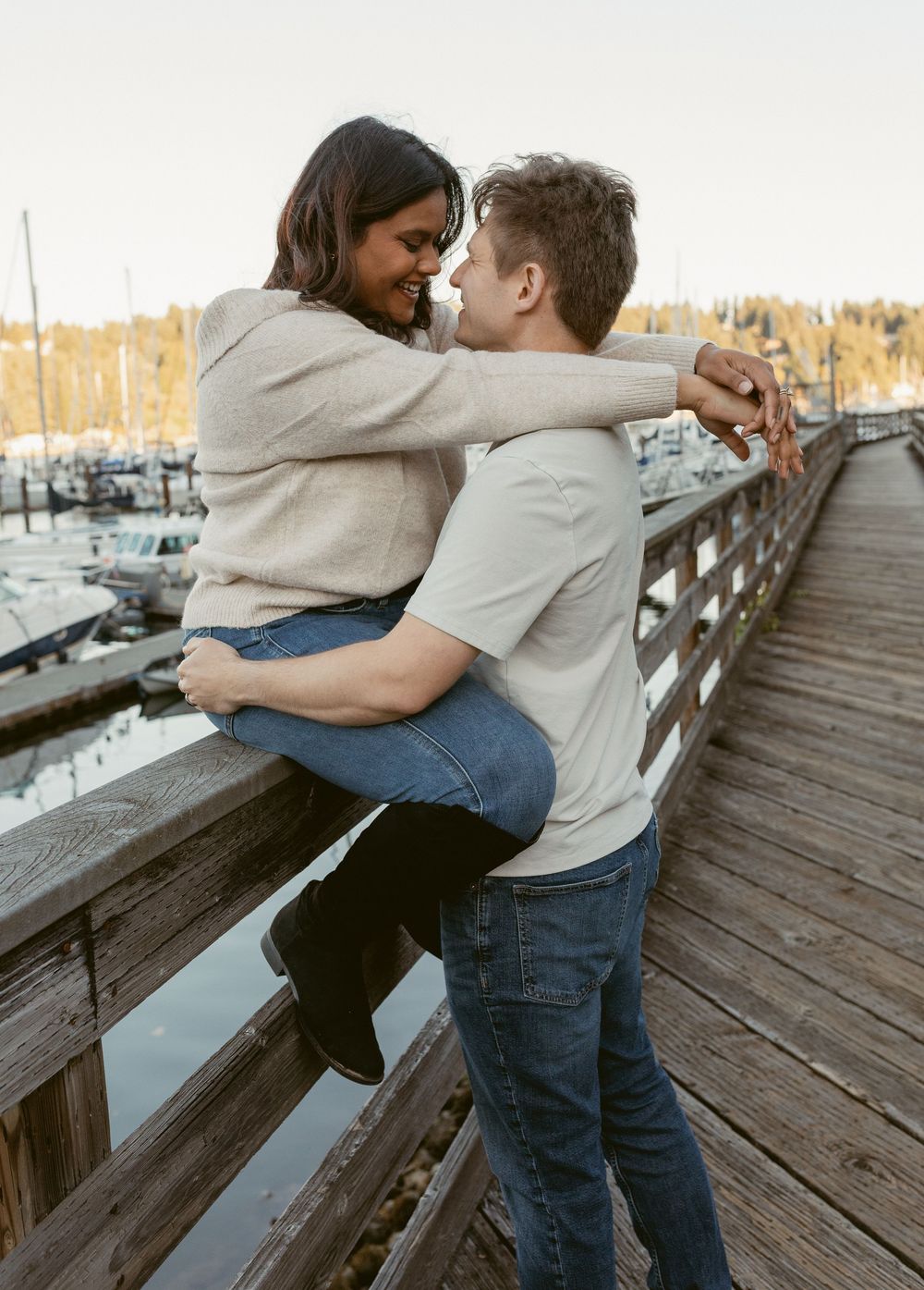 Dancing together playfully on a rustic wooden pier overlooking a peaceful marina.
