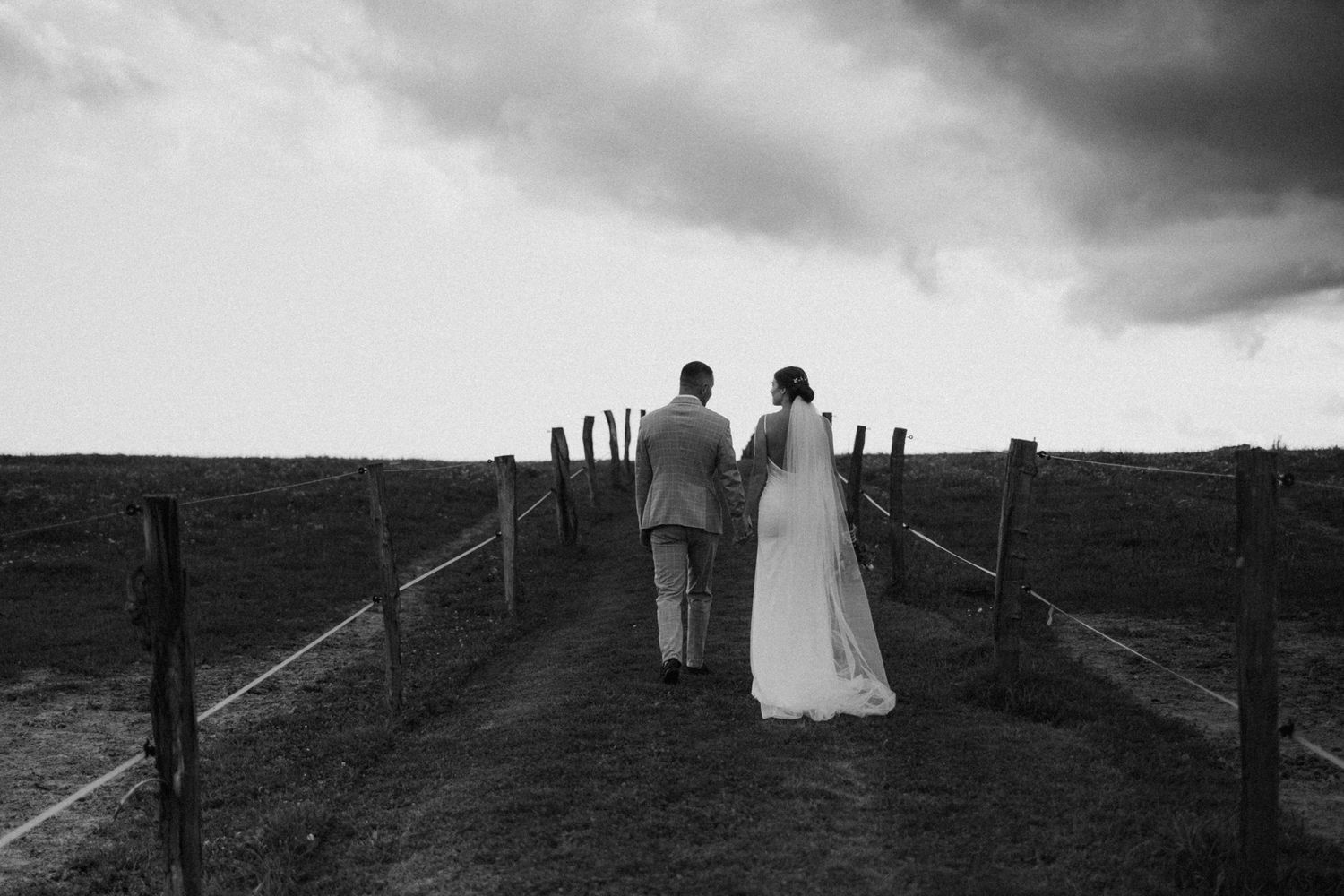 Silhouettes against a moody sky show figures walking along a hilltop path at sunset.