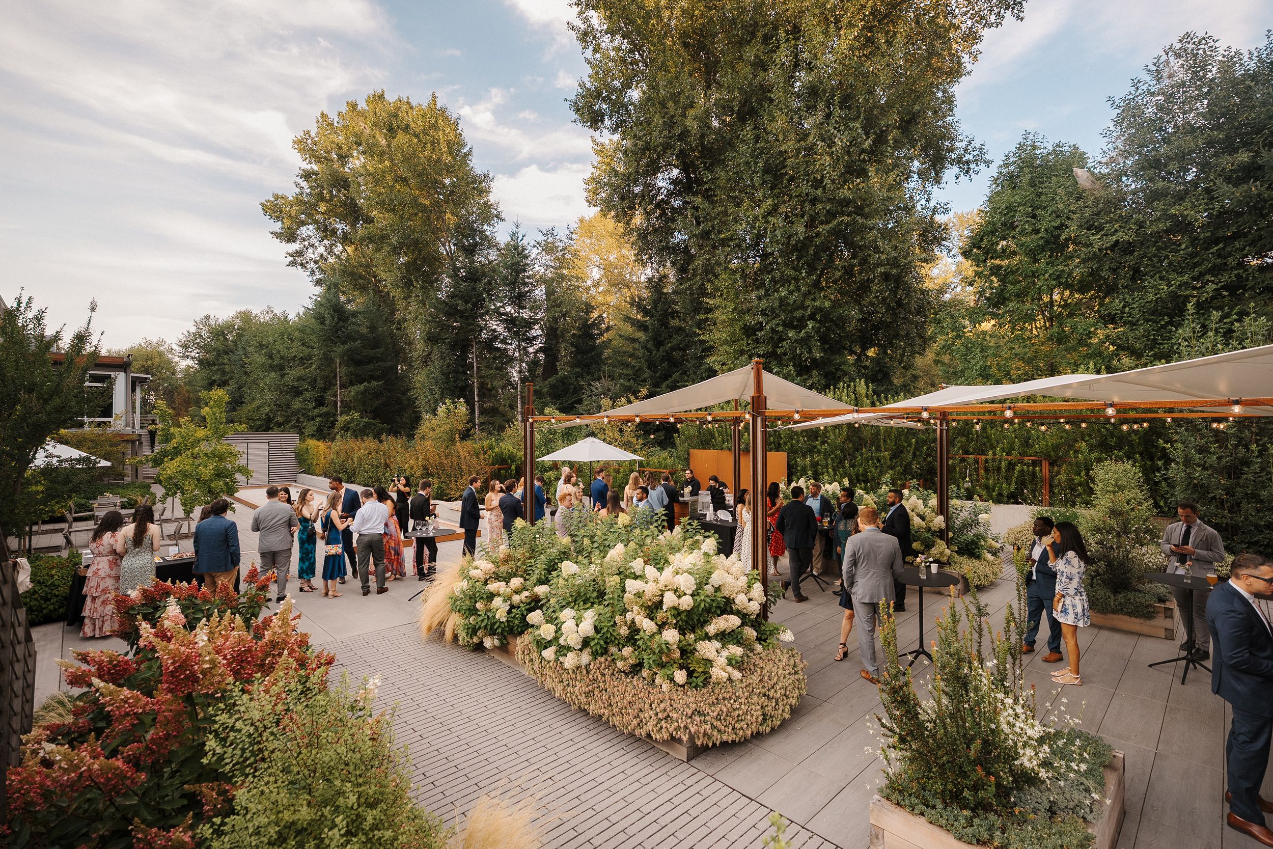 A scenic garden pathway lined with colorful flowers and trees with visitors enjoying a peaceful afternoon stroll.
