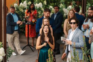 Wedding guests share joyful moments and laughter during an outdoor reception celebration.