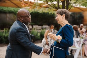 Couple shares an intimate dance moment at an outdoor wedding reception surrounded by guests and natural scenery.