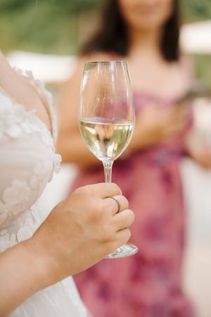 Close-up sequence of hands holding a glass of white wine in an elegant outdoor setting.