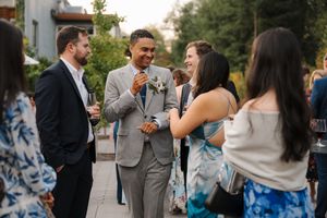 A group of people socializing at an outdoor gathering in formal attire.