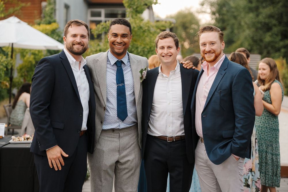 Wedding party members in formal attire smiling together outdoors at an elegant celebration.