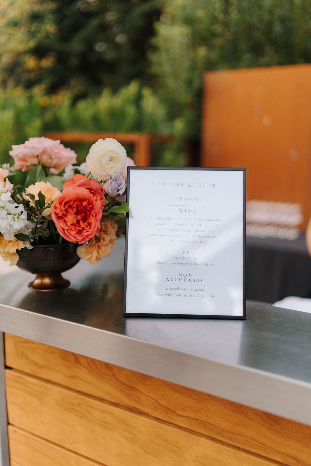 Elegant floral centerpieces and place cards arranged on a wooden table for an upscale event setting.