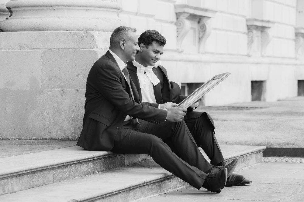 Two people in business suits sit together on stone steps in a black and white vintage photograph.
