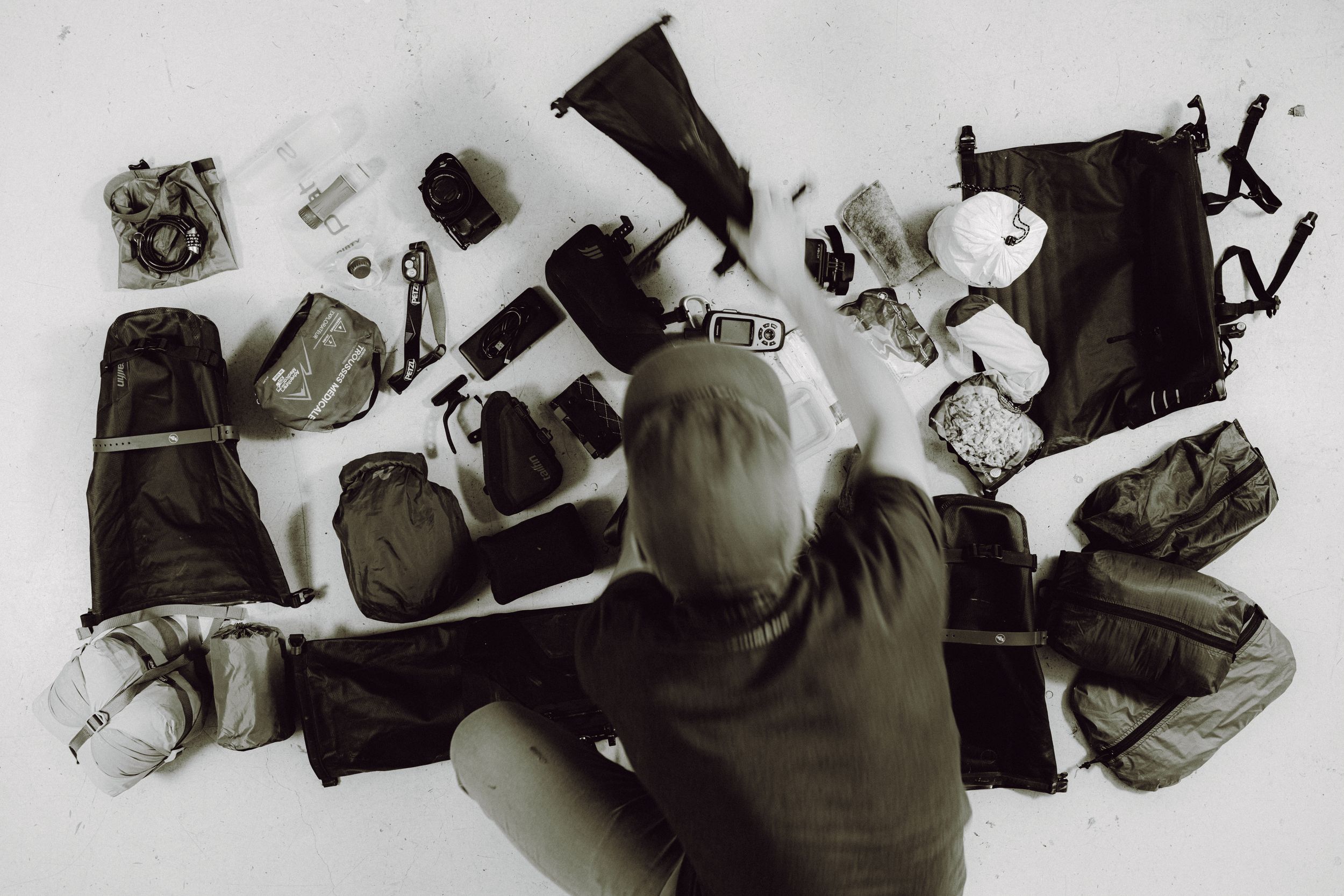 Overhead view of person lying on white surface surrounded by camera equipment and photography gear.