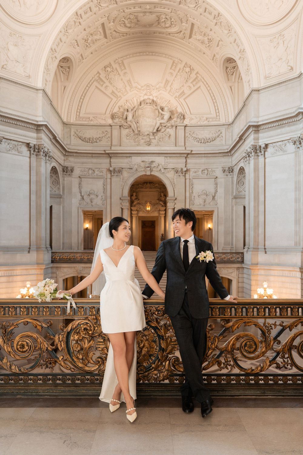 Couple shares intimate moments on an ornate balcony with decorative railings in a historic building.