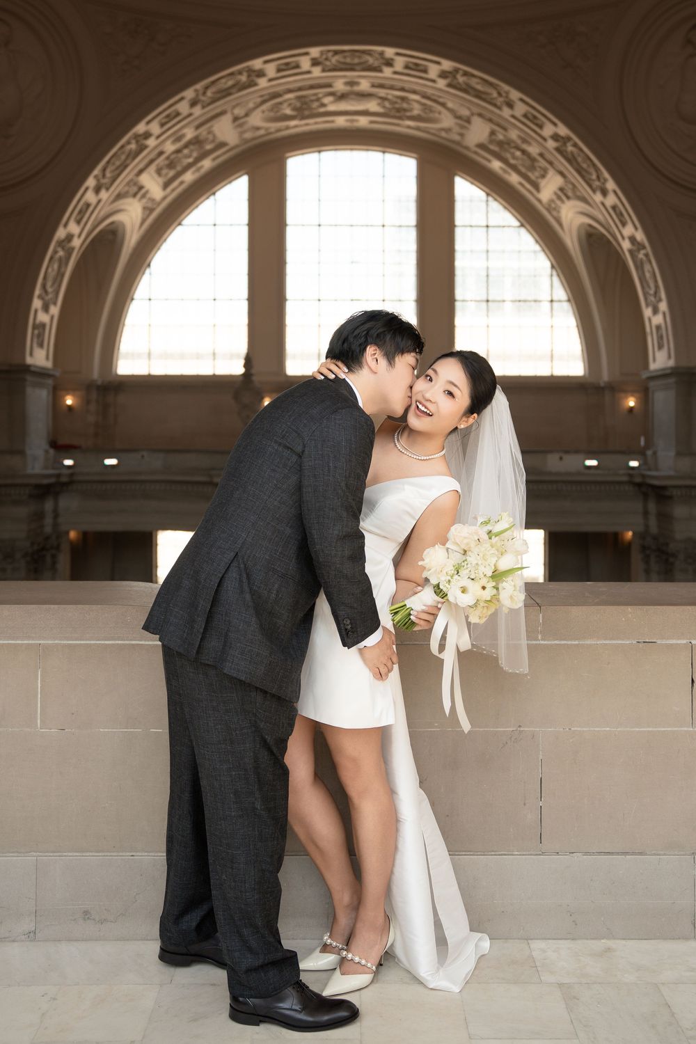 A romantic wedding photo series showing a couple in playful poses against an elegant arched window backdrop.