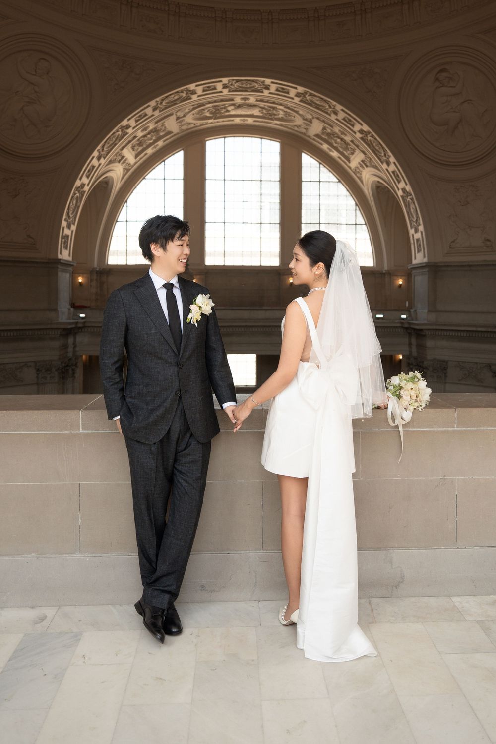 Wedding couple poses playfully in a series of romantic shots against an elegant stone wall with arched windows.
