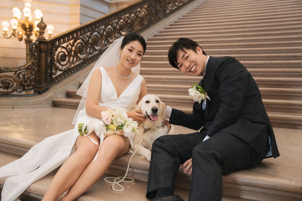 A wedding couple poses on an elegant staircase with ornate railings during their traditional ceremony photoshoot.