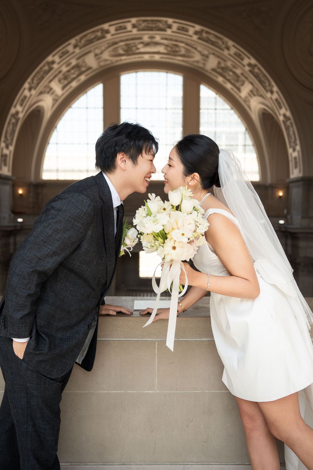 Newlywed couple shares romantic kisses in a series of photos taken in an elegant arched hallway.