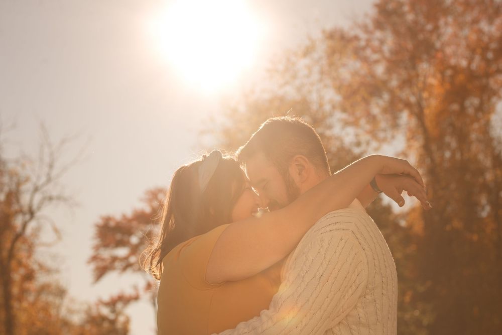 Romantic golden hour portrait of couple with sunlight creating warm backlit glow.