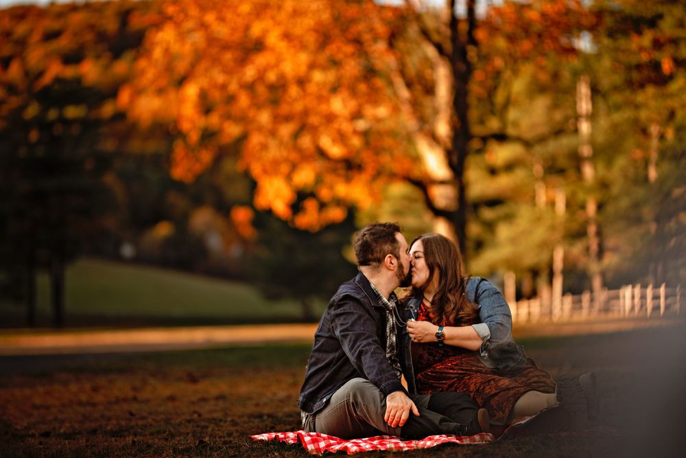 Couple sharing intimate moments during golden hour in an autumn setting.