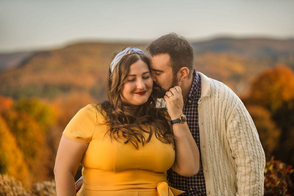 Couple sharing an intimate moment against a backdrop of vibrant autumn foliage at sunset.