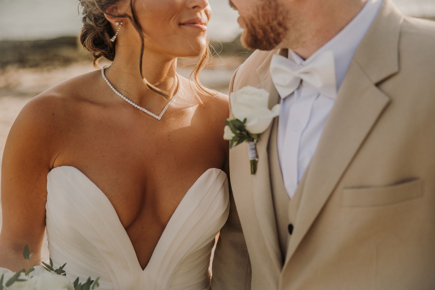 A romantic wedding couple embraces outdoors in natural light wearing elegant white dress and beige suit. El Dorado Royale Wedding Photograph