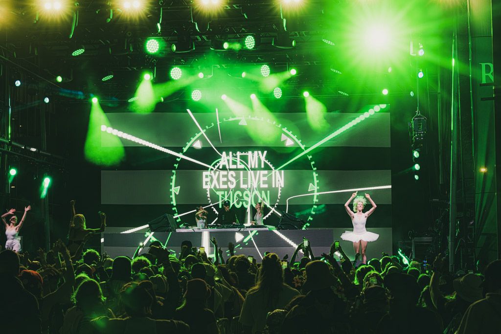Concert stage illuminated with bright green lights and laser effects creating an energetic atmosphere.