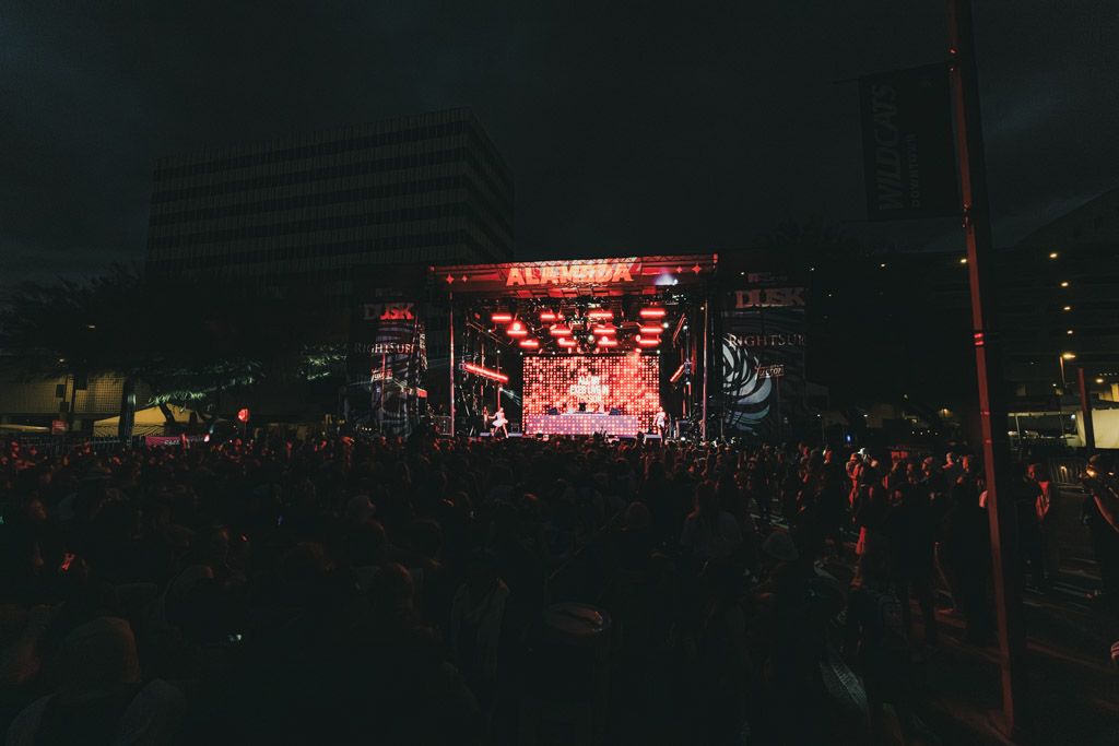 Concert stage illuminated with red lights and fog creating a dramatic nighttime atmosphere at an outdoor music festival.