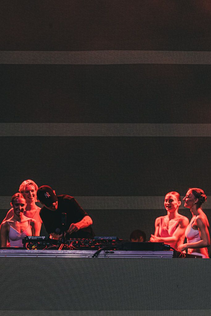 Performers in red lighting lie on stage during a dramatic dance performance.