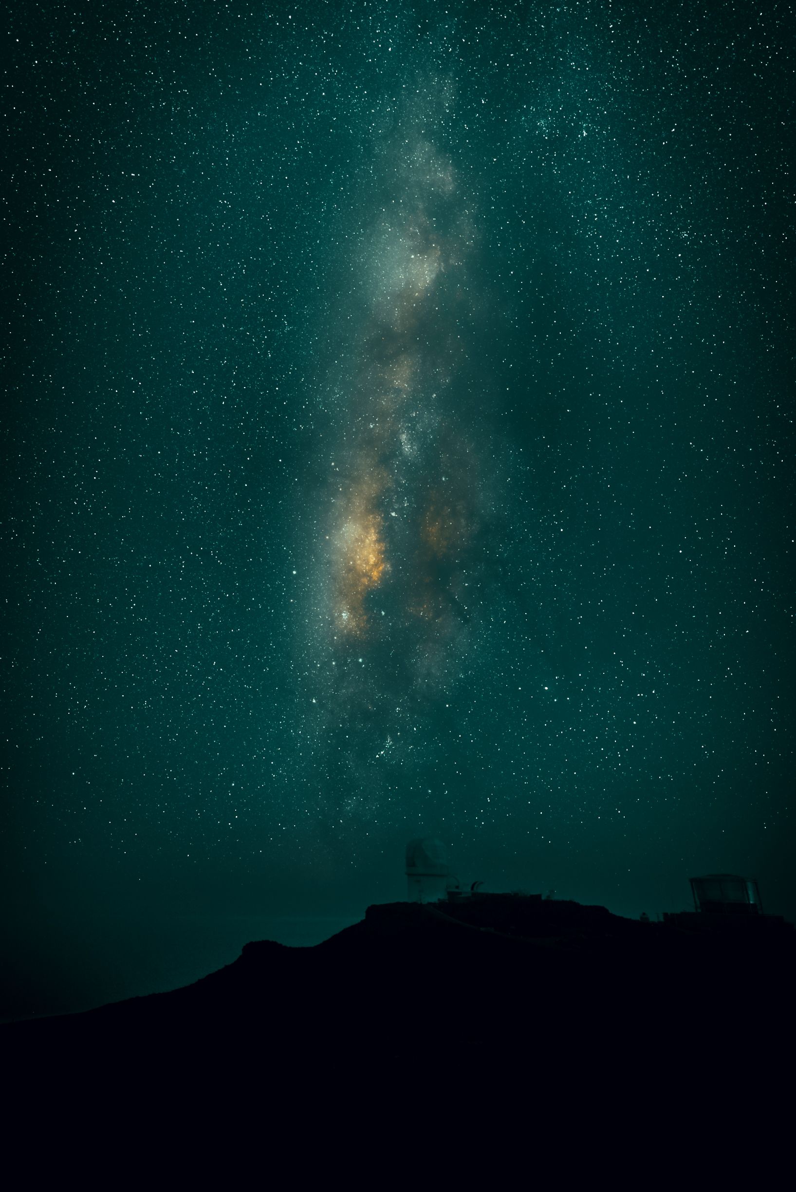 Time-lapse photography captures the Milky Way galaxy moving across a dark night sky above mountain silhouettes.
