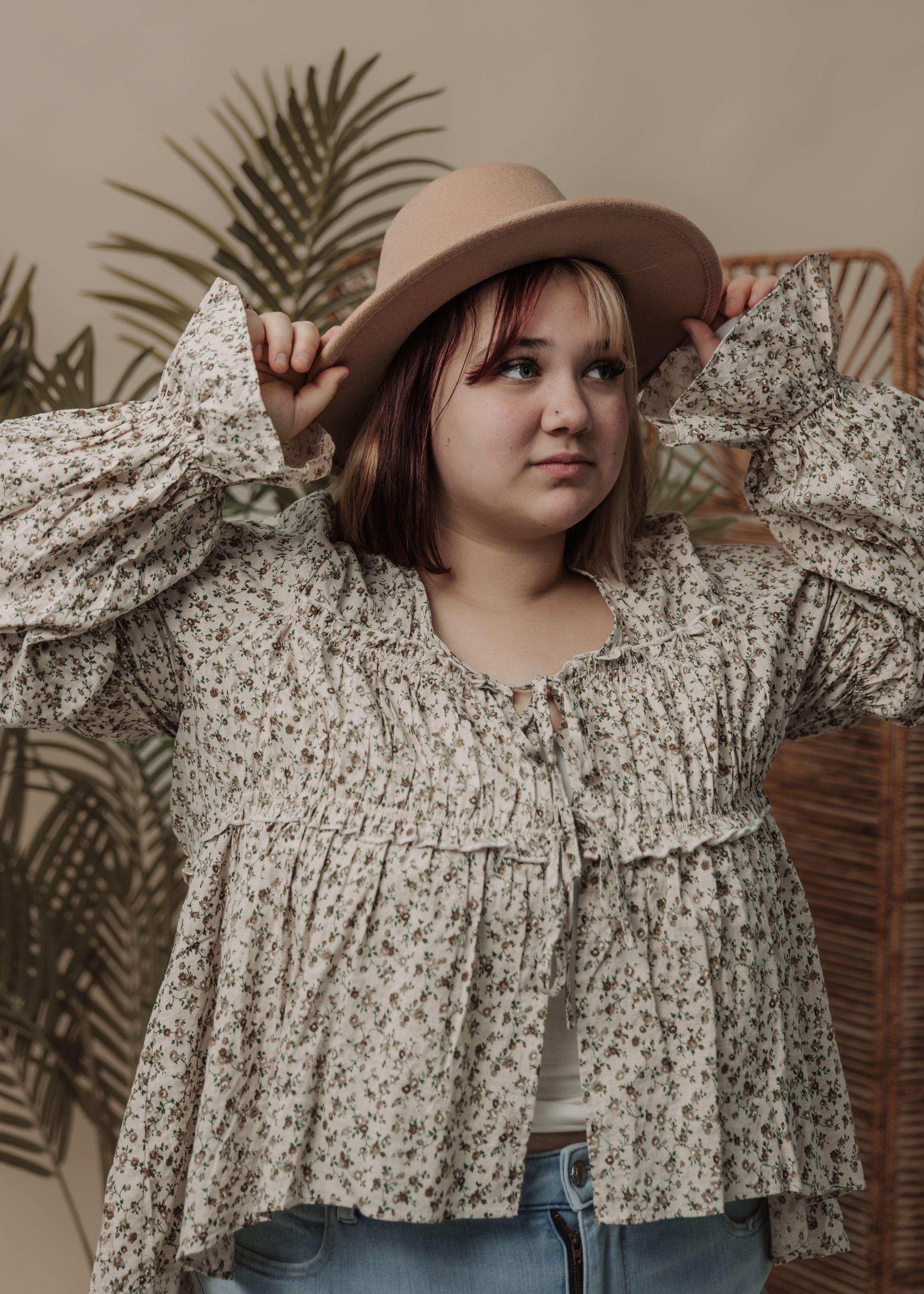A floral print ruffle dress with puff sleeves styled with a brown wide-brim hat.