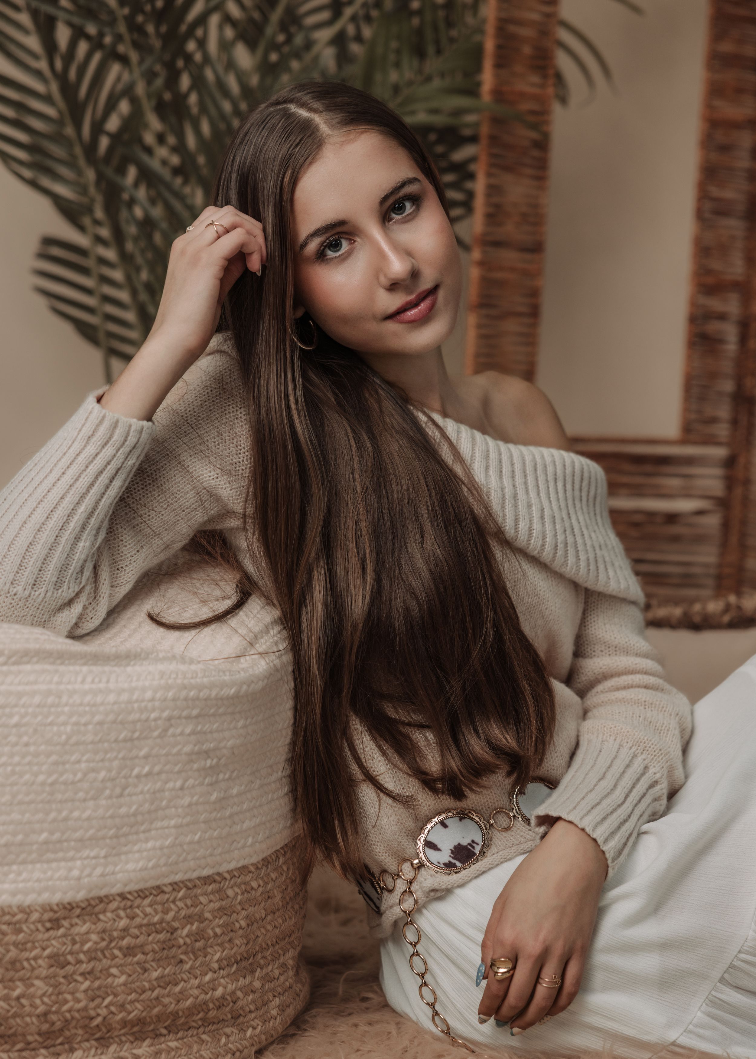 A series of cozy lifestyle photos featuring someone in a cream knit sweater lounging on white furniture.