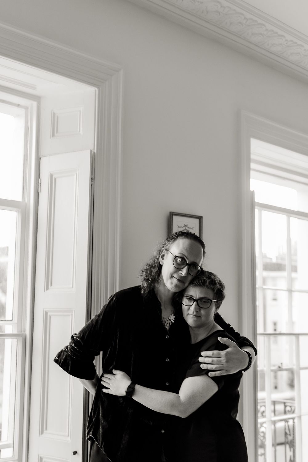 Black and white photo series showing emotional moments in a bright room with ornate moldings.