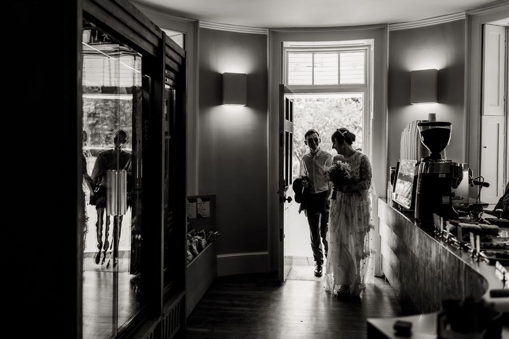 A black and white interior view of a hallway with silhouettes standing in doorway light.