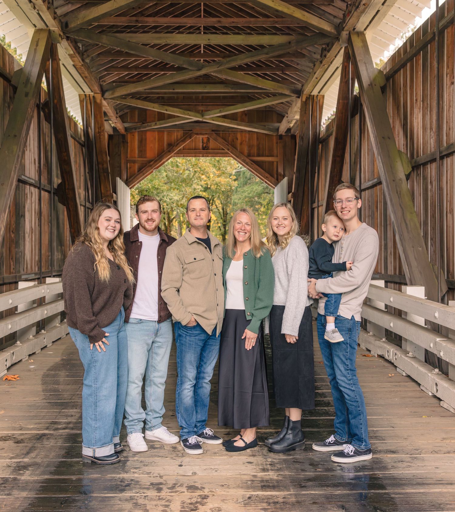 Group photo session inside a rustic covered wooden bridge with natural lighting.