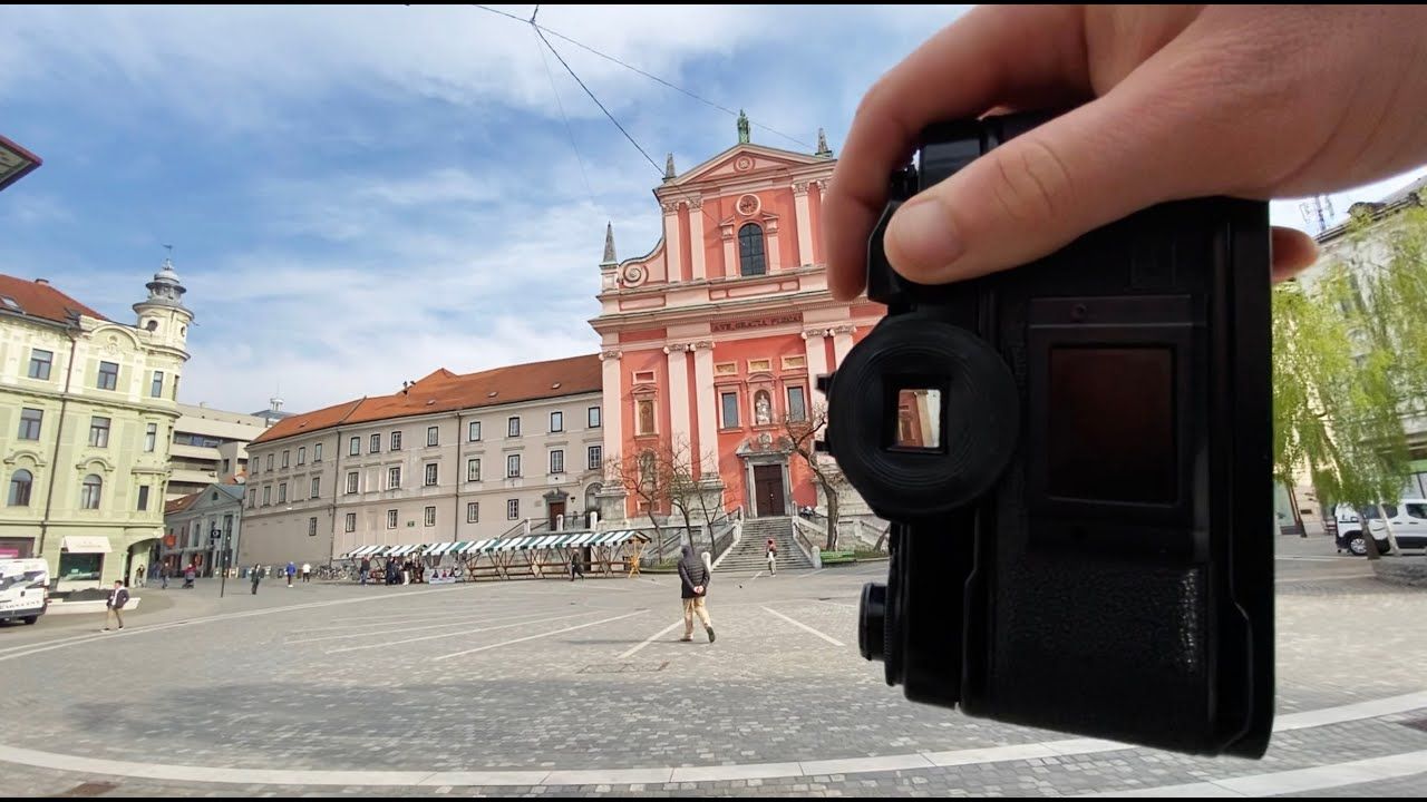 Hand holding a wallet in front of the Franciscan Church of the Annunciation in Ljubljana's Preseren Square, Slovenia.