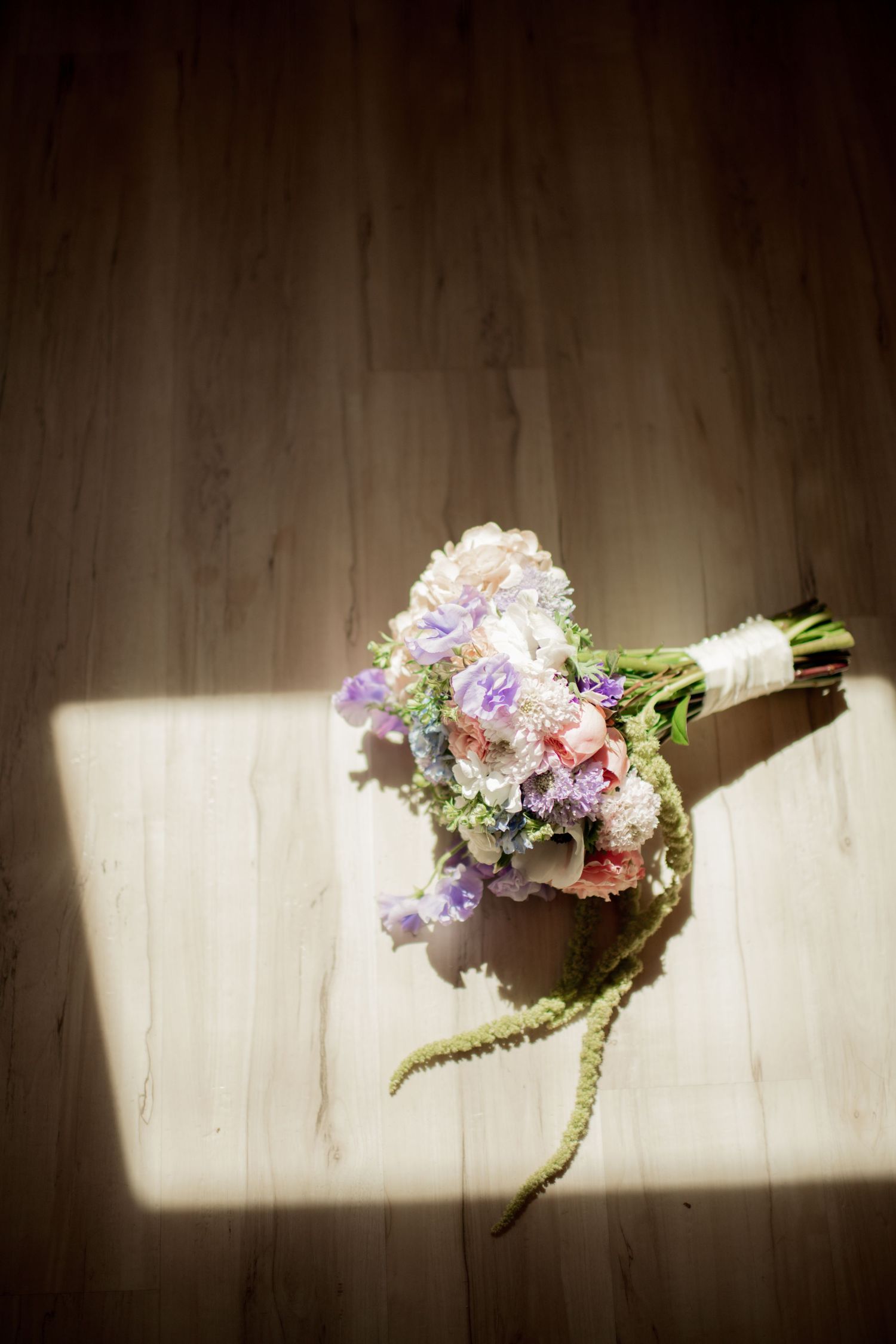 A sequence of photos showing a butterfly landing on a delicate bouquet of pink and purple flowers against a white wall.