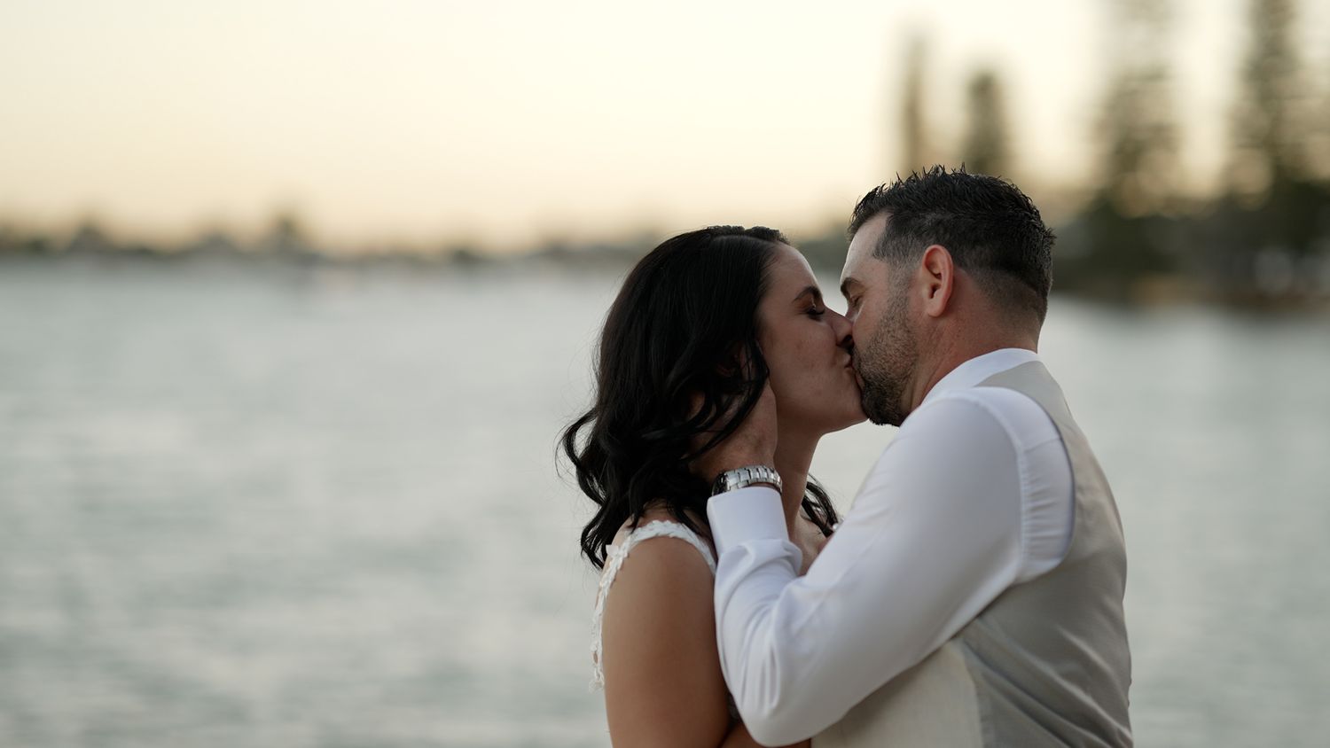 Romantic waterfront moment between newlyweds during golden hour.
