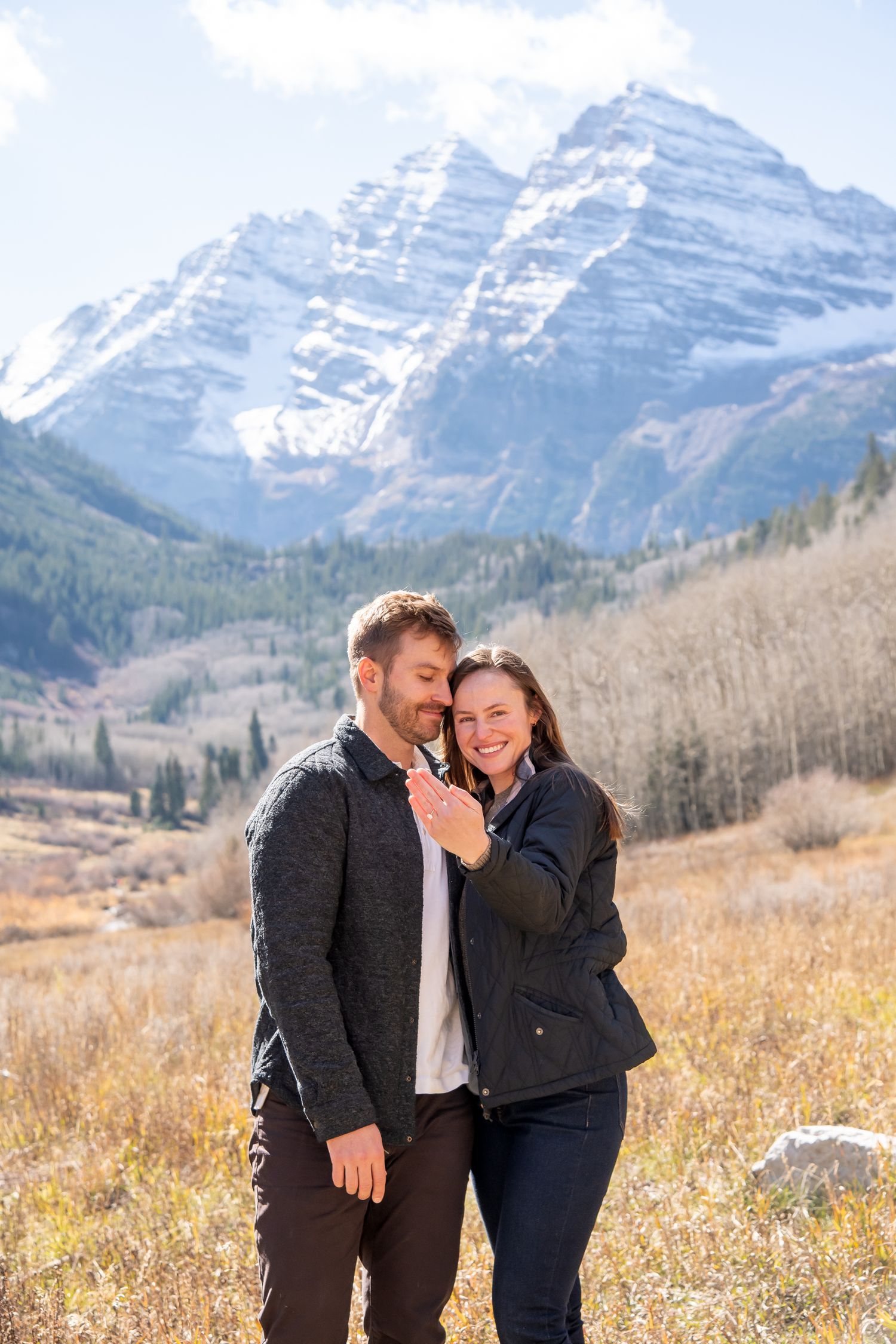 A couple together showing off engagement ring after a surprise proposal at The Maroon Bells in Aspen Colorado