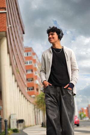 Chico con auriculares y sudadera clara sonriente y andando en Vitoria-Gasteiz, sesión de fotos para RRSS redes sociales