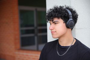 Chico con auriculares y camisa negra frente a mural urbano,  serio en Vitoria‑Gasteiz