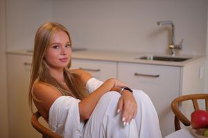 Una joven sentada en la cocina con expresión serena, en interior cálido y bien iluminado, sesión de fotos personal en Alava, Bilbao, Donosti