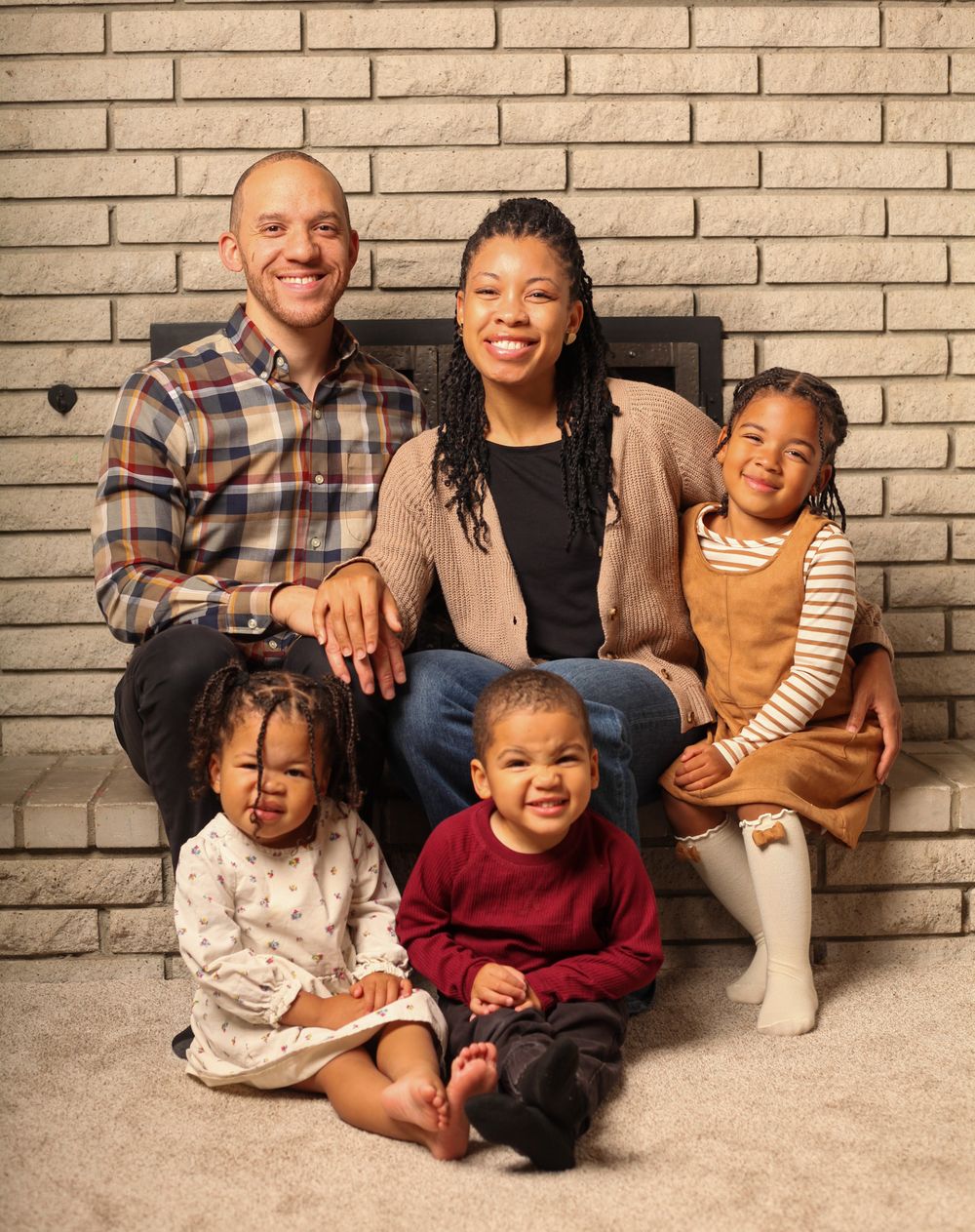 A family in coordinated outfits poses together against a brick wall in a series of casual portrait shots.