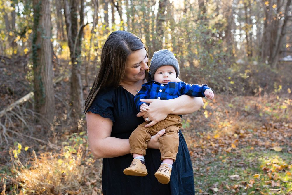 Family enjoying a peaceful autumn walk together through a sunlit forest with golden fall foliage.