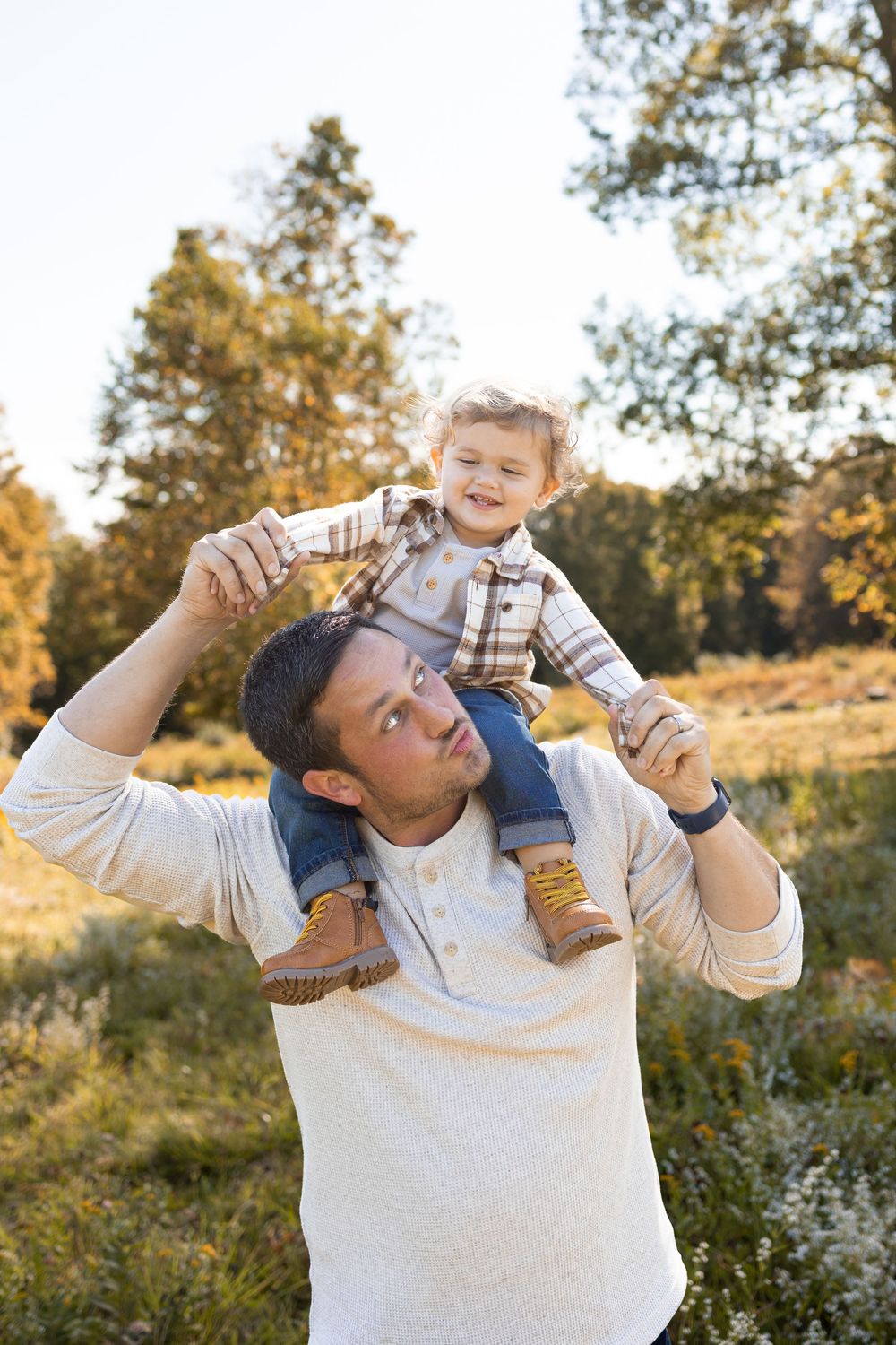A parent and child play together outdoors during golden hour in a natural setting. Fall Mini Session