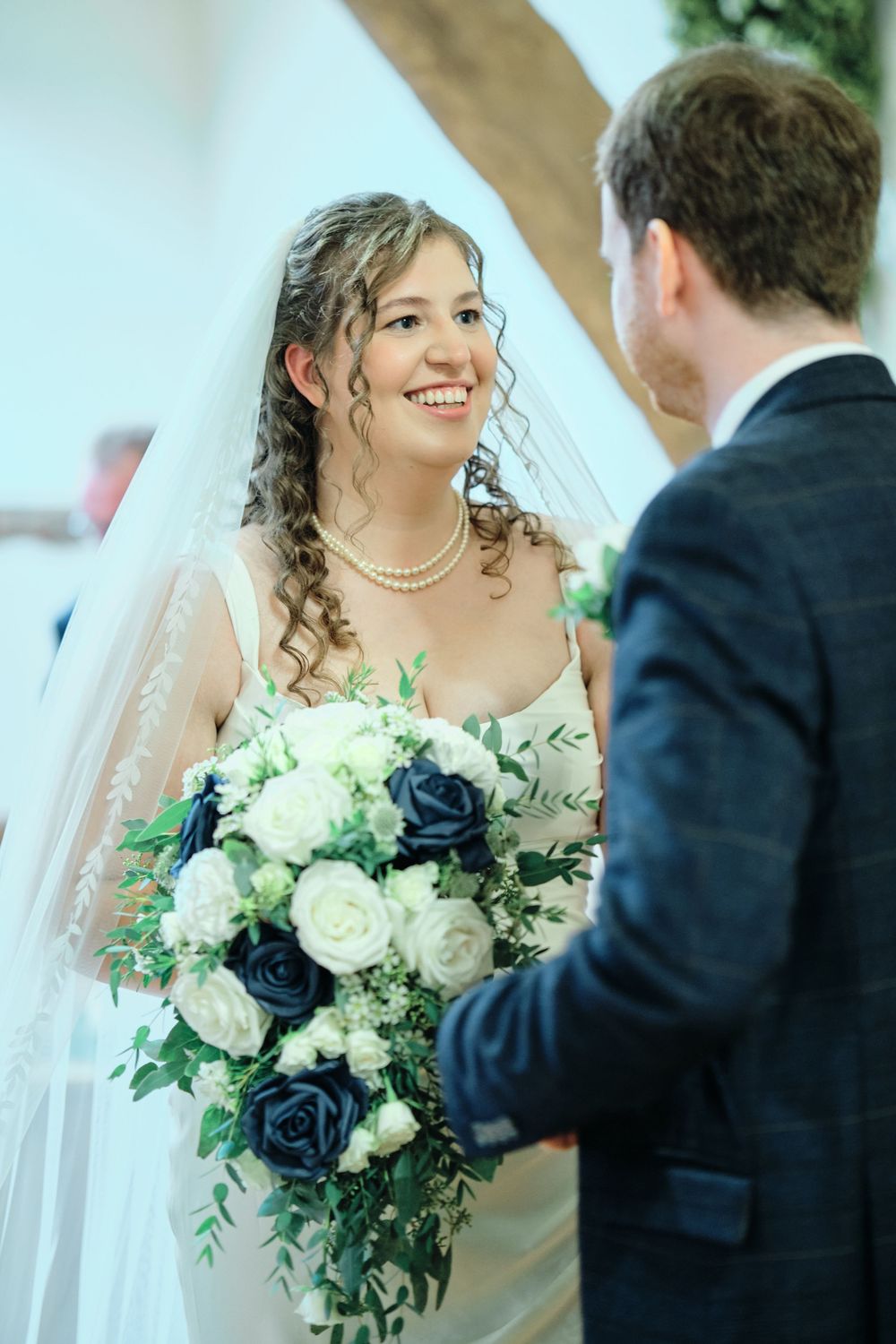 Bride and groom share intimate moments in a wedding photo collage featuring white and navy blue floral bouquet.