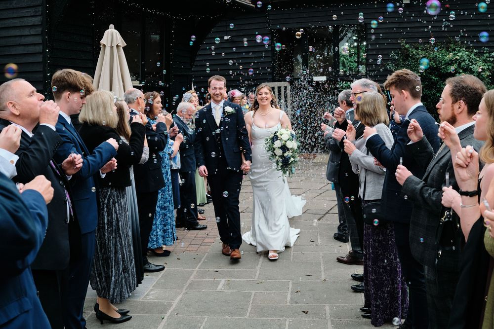 Wedding guests line up to throw confetti at a joyful outdoor celebration.